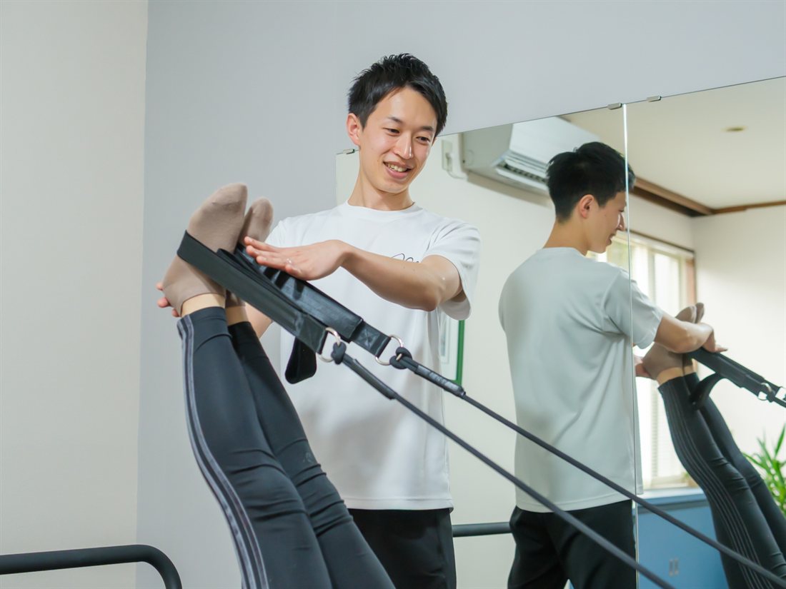 理学療法士 佐々木拓良がマシンを使って個別に指導している場面