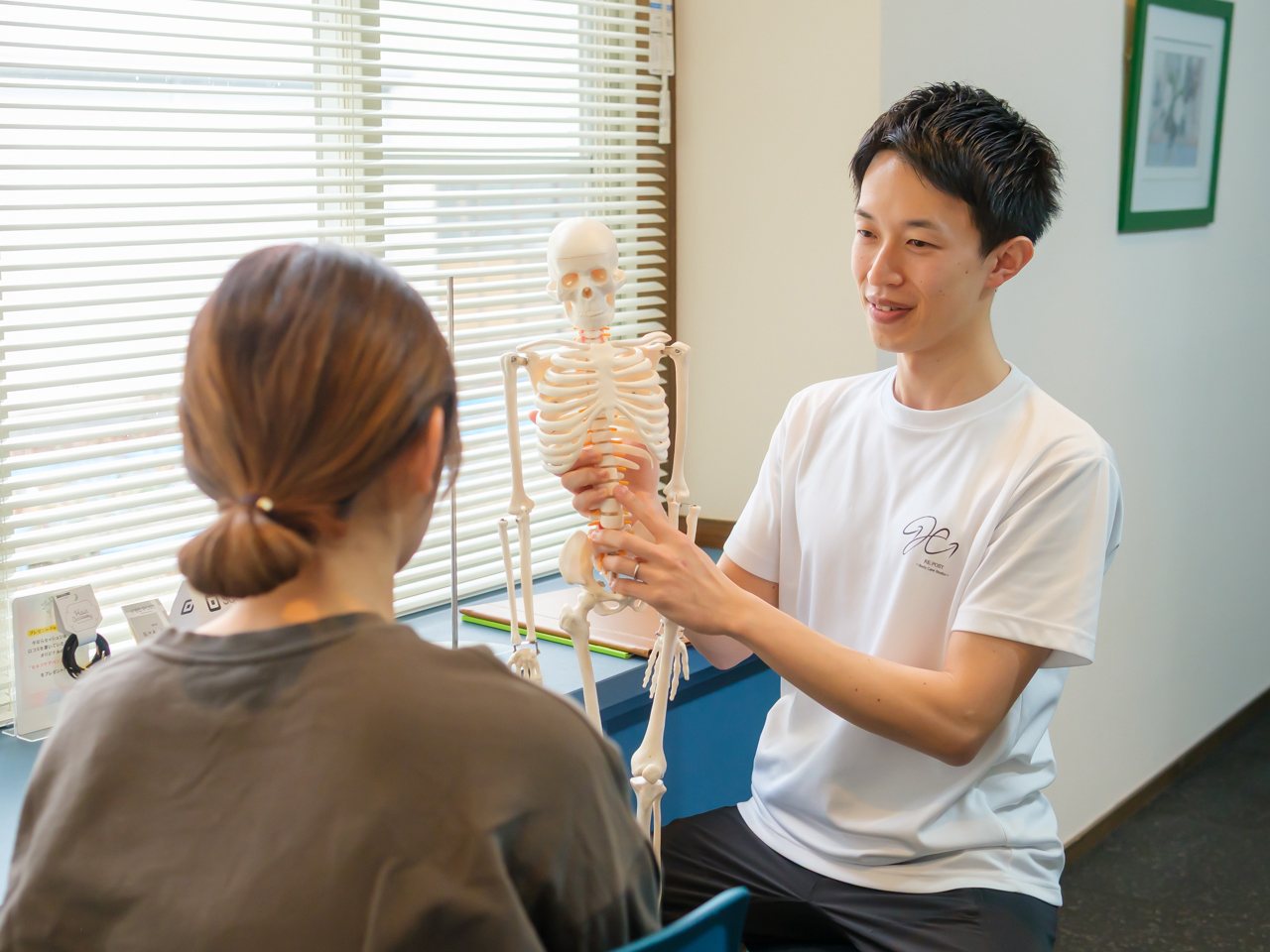 理学療法士が骨模型を使って身体のつながりを説明している場面